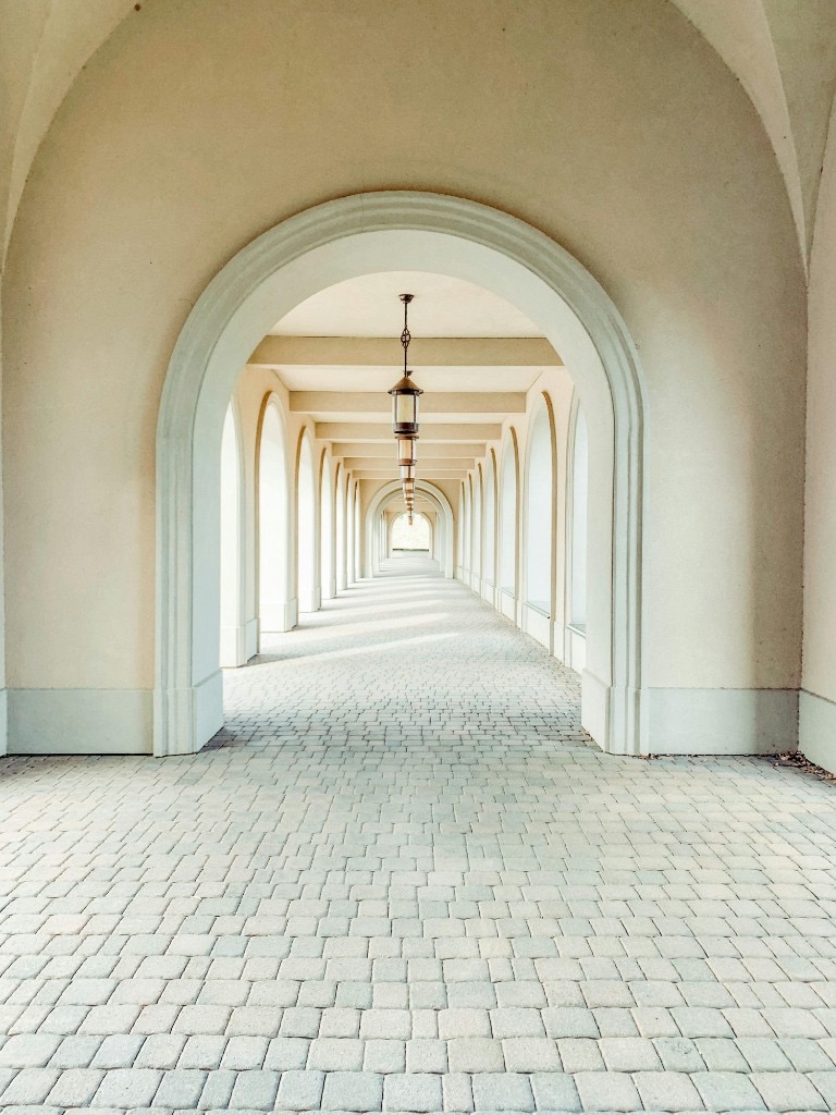 Symmetrical arched corridor with repeating vaults and pendant lanterns, suggesting two parallel paths leading to the same destination