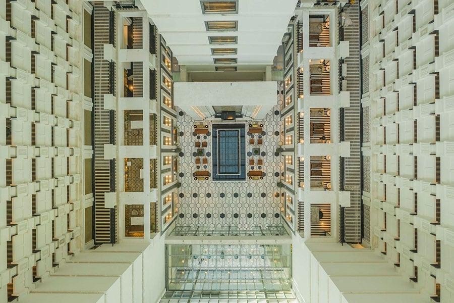 Bird's-eye view of a modern multi-story building atrium with symmetrical balconies and a patterned lobby floor, symbolizing the structured overview financial statements provide