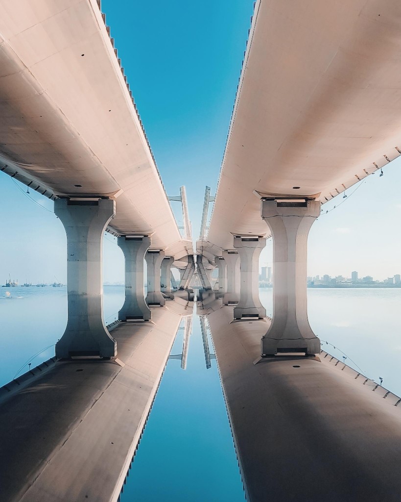 A symmetrical modern bridge reflected perfectly in still water, symbolizing matching and balance