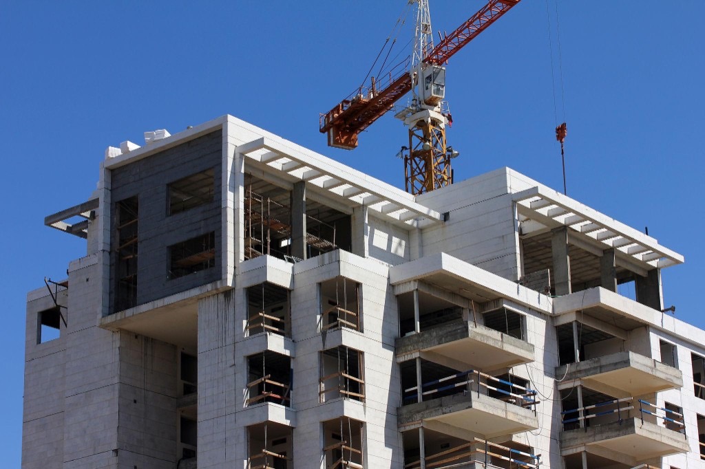 A multi-story building under construction with a tower crane, symbolizing a large project billed in stages through progress invoicing.